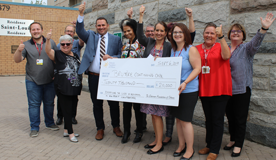 groupe of bruyere employees with thmbs up presenting cheque