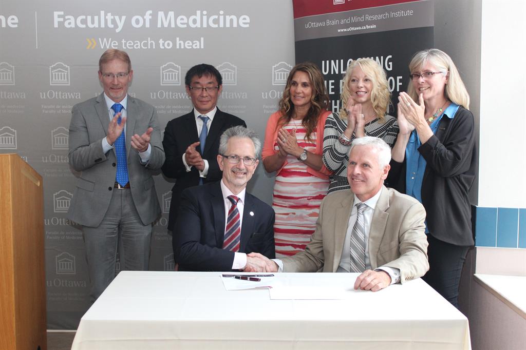 Four mens and three womans behind a table signing a contract